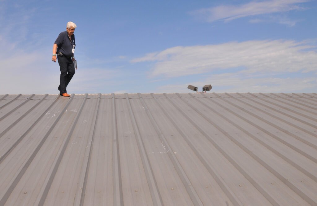 Inspector examining hail impact marks on a metal roof