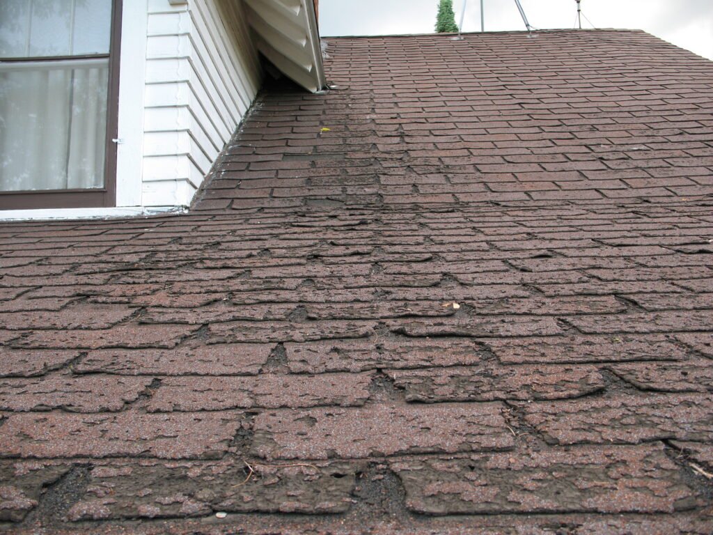 Aging asphalt roof with pronounced wear near the eaves